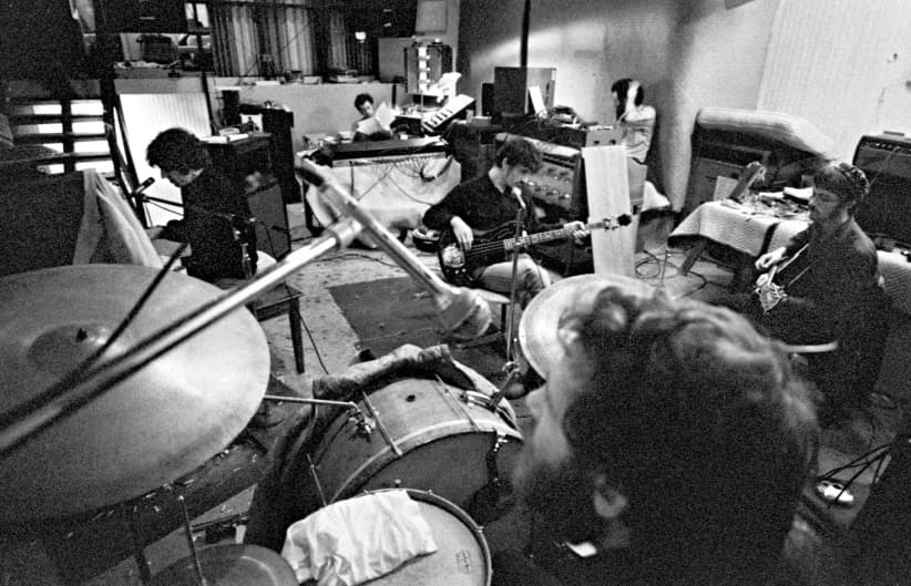 1969. In the studio set up in Sammy Davis Jr's pool house. Richard at the piano, me reading a manual and trying to figure out how the mixing board works, Rick, Garth scratching his head again, Levon in the foreground and Robbie.